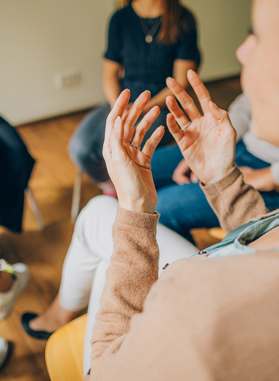 Teilnehmerin berichtet gestikulierend in einer Gruppentherapie von ihren Erfahrungen