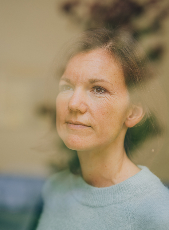 Eine Frau schaut nachdenklich durch das Fenster nach draußen