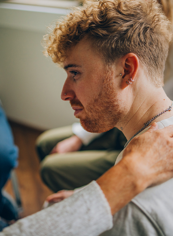 Ein junger Mann erfährt in der Gruppentherapie Unterstützung von einer Teilnehmerin