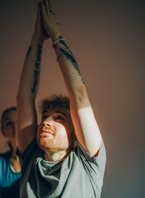 Junger Mann macht unter Anleitung seiner Therapeutin eine Yogapose in der Bewegungstherapie