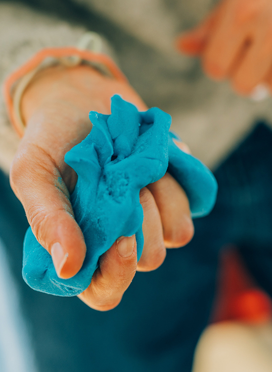 Eine Hand formt blaue Knete in der Kunsttherapie