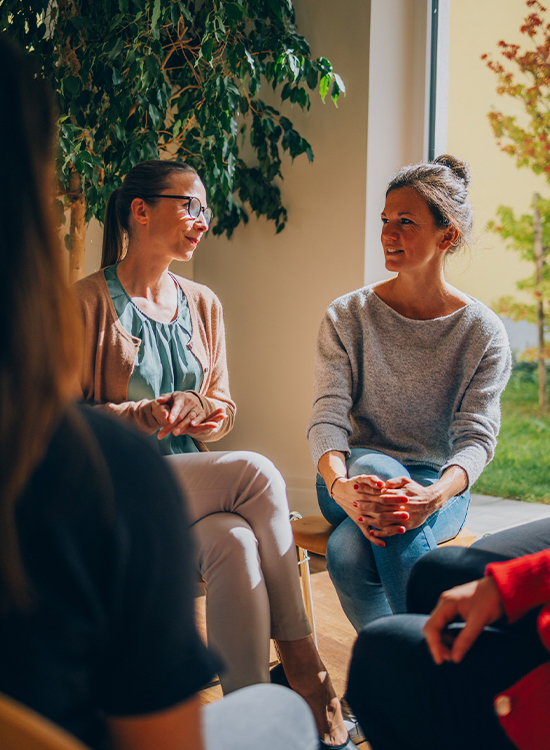 Zwei Frauen unterhalten sich angeregt in einer Gruppentherapiegruppe
